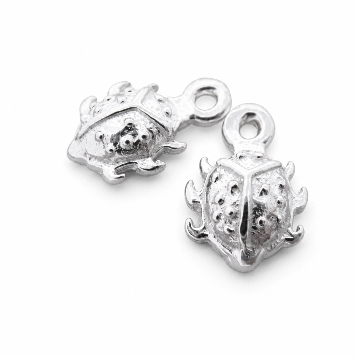Pair of sterling silver 8mm ladybird sleeper charms on a white background